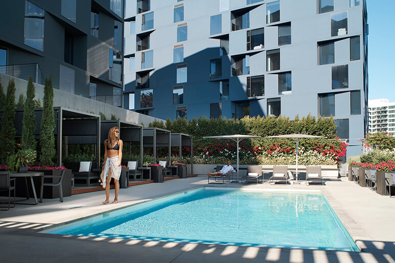 Woman walking along the outdoor pool with lounge chairs