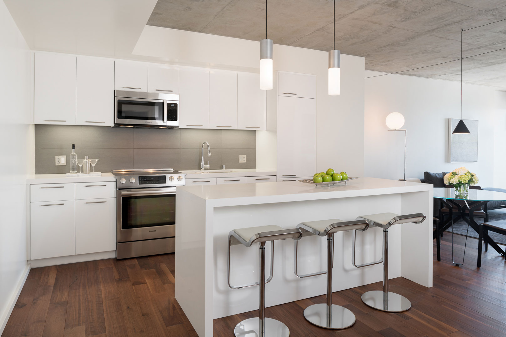 Kitchen with white furnishings, stainless steel appliances, floating island and bar stools